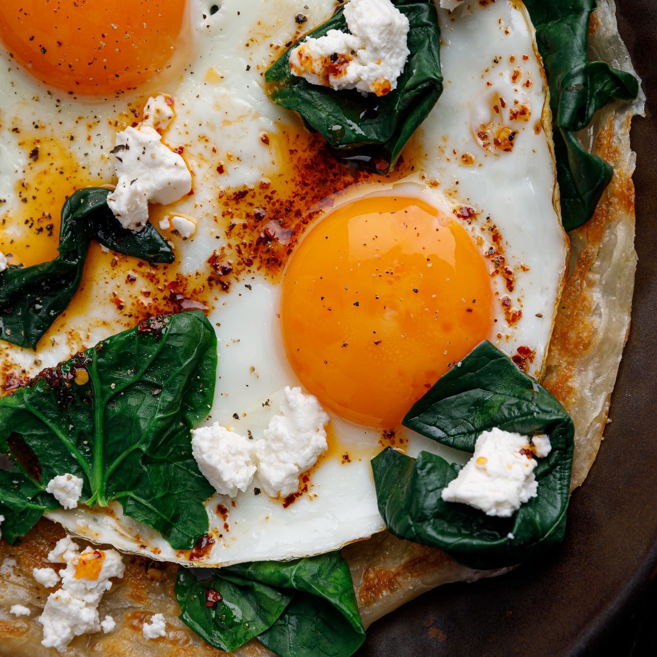 Слоеная лепешка роти с глазуньей, сыром фета, припущенным шпинатом и острым маслом