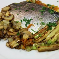 Дорада, запеченная на овощной подушке, в бумажном конверте