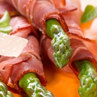 Спаржа, завернутая в ветчину серрано, с листьями салата, миндалем и виноградом