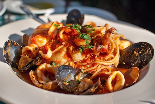 Паста с морепродуктами, зеленью и чесноком в томатном соусе